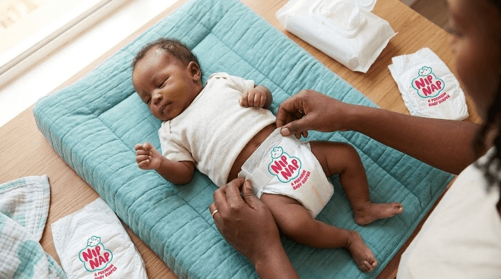 Kenyan mother changing her newborn baby's nappy on a changing mat at home